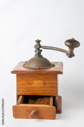 Close-up of old wooden coffee grinder, drawer with open ground coffee with defocused handle, on white background, vertical