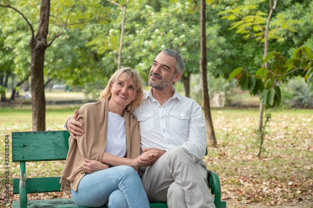 Happy Senior Caucasian couple hugging and holding hand together in while sitting at bench in the park. Happy Senior Caucasian couple hugging and holding hand together in while sitting at bench in the park.