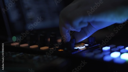 DJ mixer in club night party bright colorful buttons, fingers with buttons. Music controller in night club, dark shot, music in night clubs 