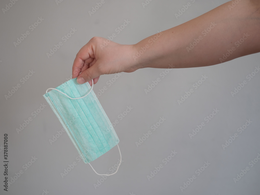 Female hand holds blue surgical mask with rubber ear straps. Typical three-layer surgical mask for covering the mouth and nose. (Clipping path). Protection concept from corona virus Female hand holds blue surgical mask with rubber ear straps. Typical three-layer surgical mask for covering the mouth and nose. (Clipping path). Protection concept from corona virus