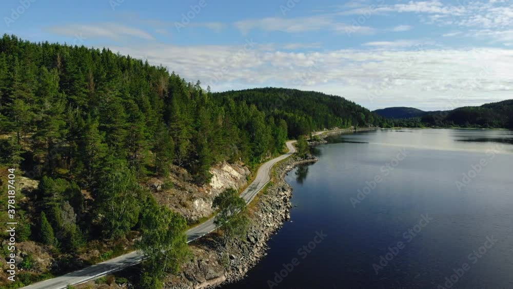 Aerial view of empty forest road and the lake on the side. Beautiful mountain road. Driving on the mountain road. Road trip. Mountain forest lake landscape. Aerial view of empty forest road and the lake on the side. Beautiful mountain road. Driving on the mountain road. Road trip. Mountain forest lake landscape.