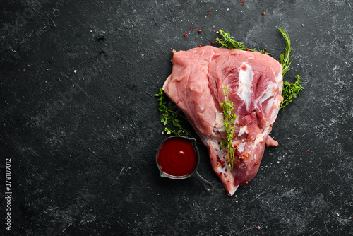 fresh raw pork shoulder with ingredients and spices on kitchen background. Meat. Top view. Rustic style.