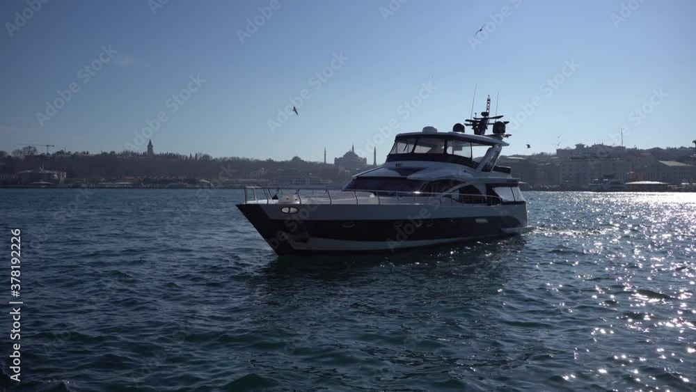 A beautiful white yacht sails from the port along the blue strait in Istanbul. Seagulls fly by ship in Turkey. A beautiful white yacht sails from the port along the blue strait in Istanbul. Seagulls fly by ship in Turkey.