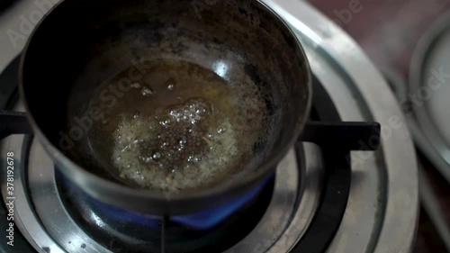 Black Peppercorn Put In A Small Deep Pan With Cooking Oil Over The Stove. - Close up-topdown Shot photo