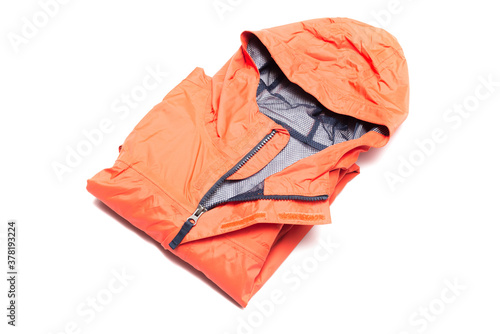 Folded orange zipper windbreaker jacket, rain proof and waterproof hiking Gore-Tex jacket hoodie. Track jacket sport nylon full zip isolated on white. Folded clothes. Outer layer garment for travel.