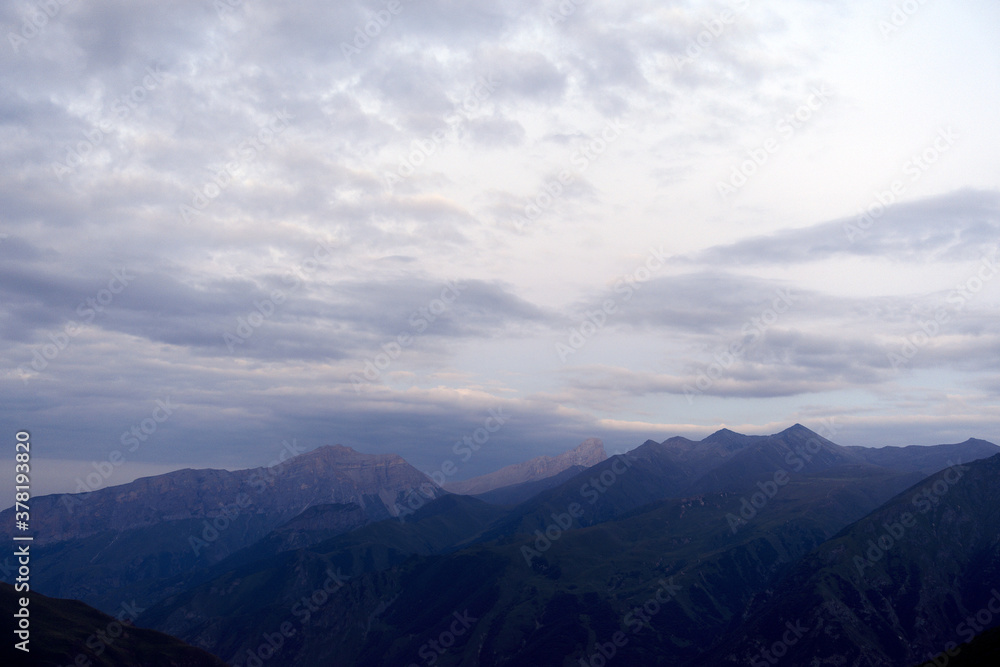 Silhouettes of mountains in the evening haze. Mountain ranges at sunset. Dusk.