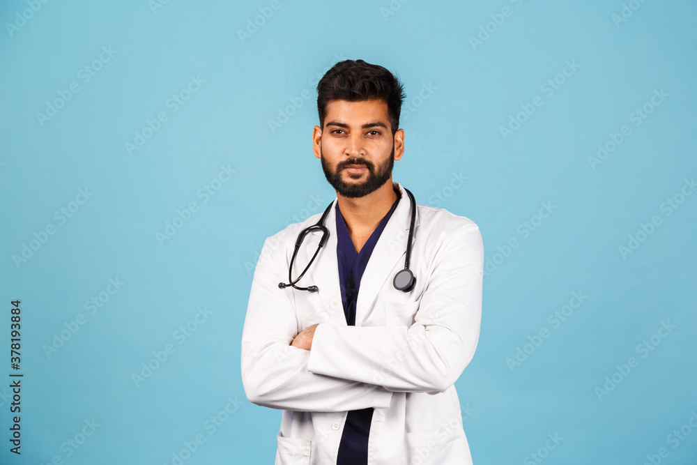 Handsome modern Indian / Asian doctor with stethoscope, in uniform on blue background Handsome modern Indian / Asian doctor with stethoscope, in uniform on blue background