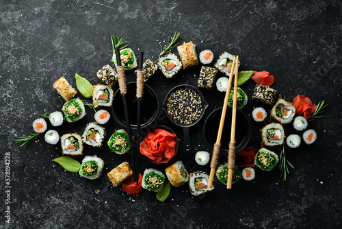 Set of tasty sushi and maki rolls on black stone background. Japanese food. Top view. Free space for your text