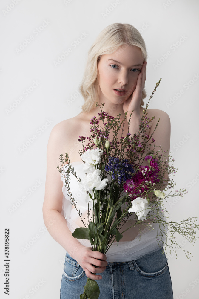Charming young woman with flowers standing against white background Charming young woman with flowers standing against white background