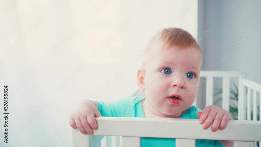 infant boy standing in baby crib and looking at camera at home infant boy standing in baby crib and looking at camera at home