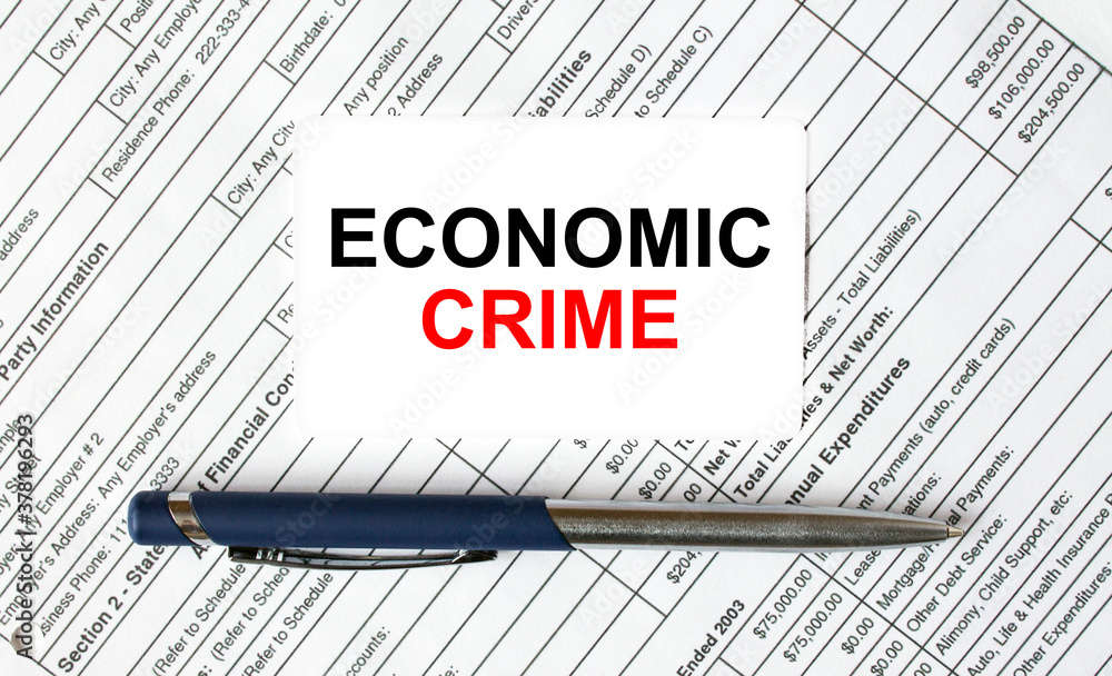 Text Economic Crime written on a business card lying on financial tables with a blue metal pen Text Economic Crime written on a business card lying on financial tables with a blue metal pen