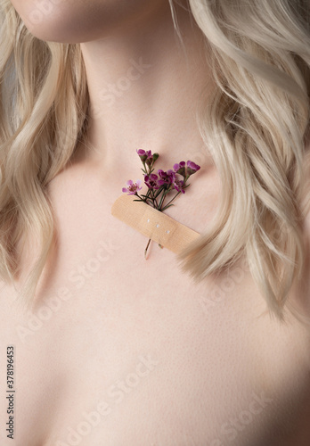 Young woman with lovely flowers taped to her skin