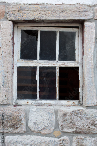 Altes verwittertes Fenster aus Holz in einer massiven Steinwand eines alten verlassenen Hauses