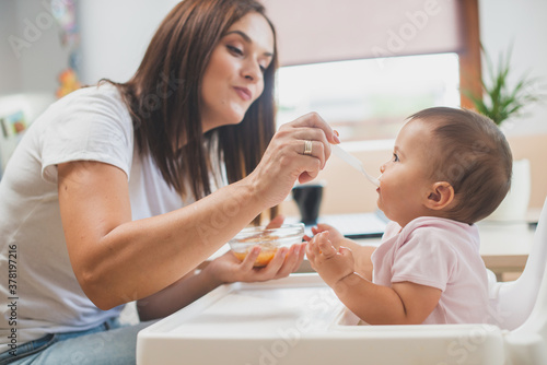 Mother feed her little daughter with a spoon