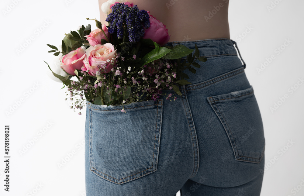 Young woman wearing blue jeans with flowers in pocket