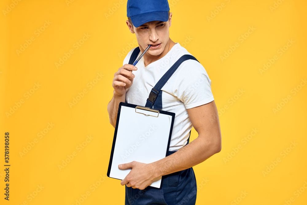 Man in working uniform documents rendering of services delivery service yellow background Man in working uniform documents rendering of services delivery service yellow background