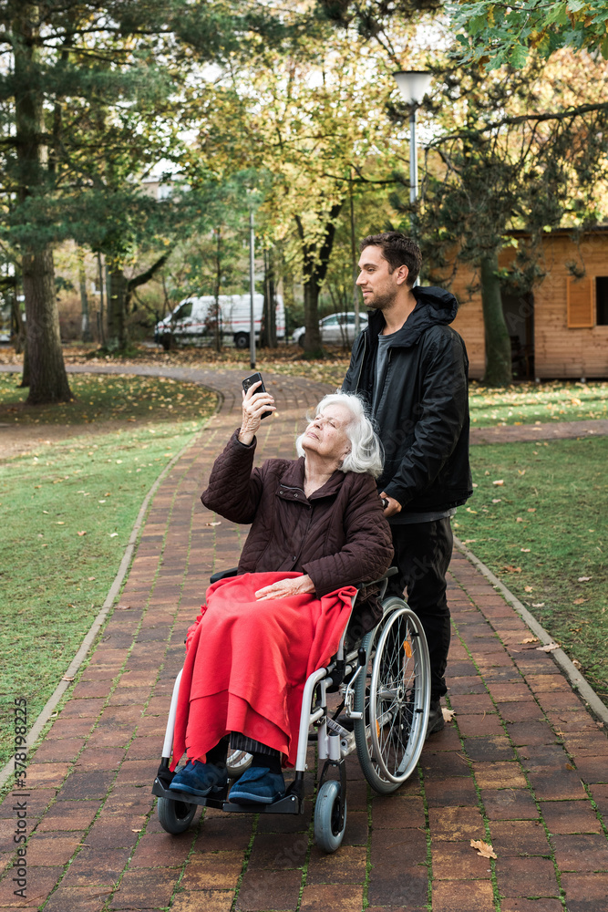 Old woman enjoys music from her son's smartphone
