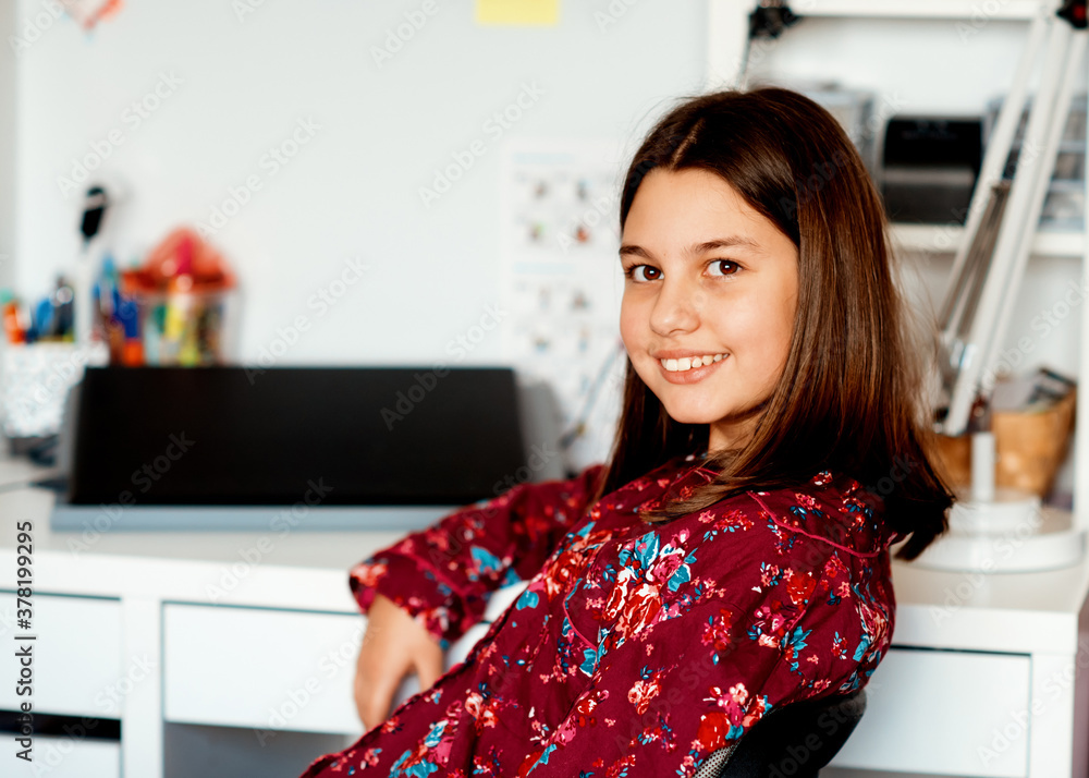 Portrait of a girl in pajamas sitting at the table and smiling Portrait of a girl in pajamas sitting at the table and smiling
