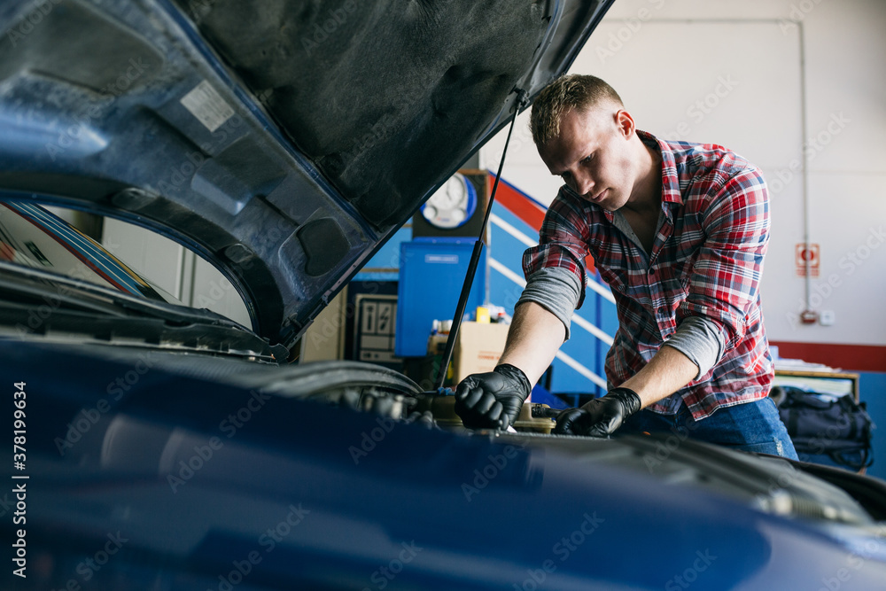 Man in black gloves repairing car engine with wrench Man in black gloves repairing car engine with wrench
