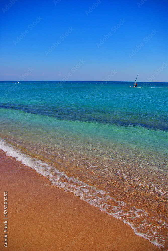 The sandy strip of beach and blue clear sea