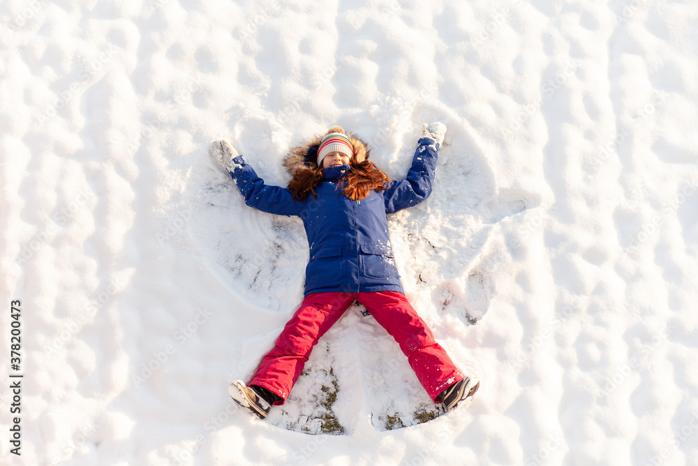 Happy elementary-age girl making a snow angel Happy elementary-age girl making a snow angel