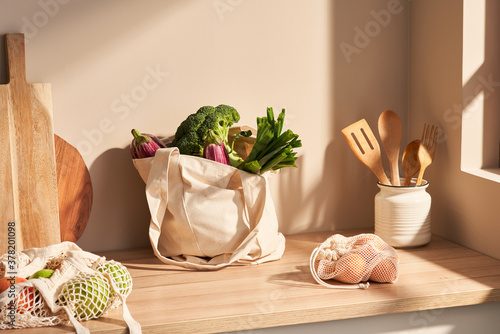 Cotton bags with groceries near wooden utensils in kitchen photo