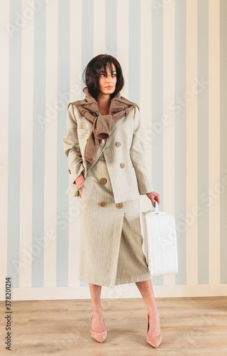 Woman holding on hand a white vintage luggage. photo