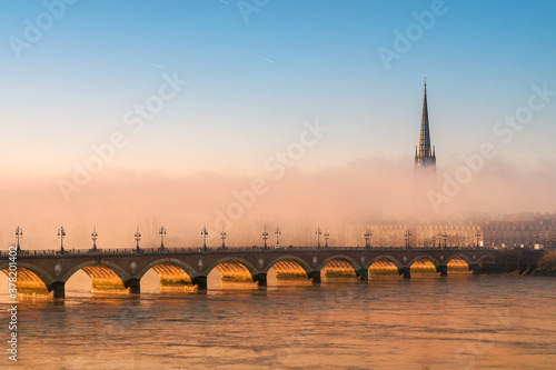Basilique Saint-Michel sous la brume avec le Pont de Pierre au lever du soleil le long de la Garonne photo
