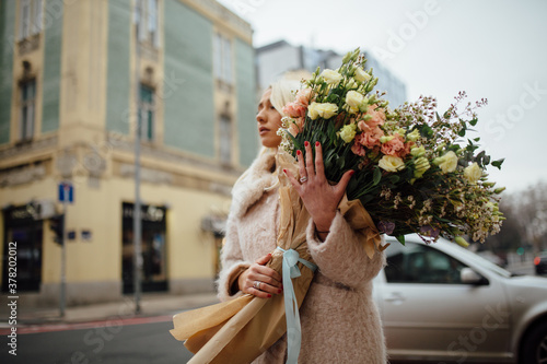 A Portrait Of A Girl Holding A Beautiful Bouquet On A City Street Looking Into The Dustance photo