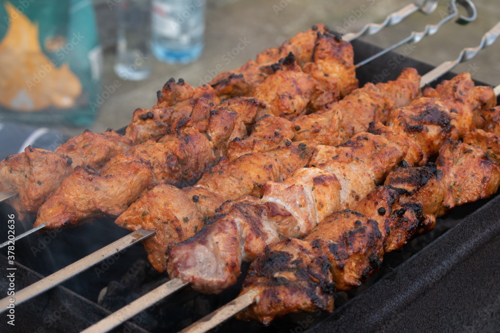 Making barbecue on a metal skewer. Grilled meat cooked on the barbecue. Skewers of fresh beef meat cut into slices. Traditional oriental dish, barbecue. Charcoal and flame grill
