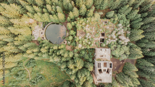 Top aerial view of abandoned water reservoir (tank) and buildings of old tin mine in Rolava,Ore mountains,Czech Republic. Beautiful nature from above.Looking straight down with a satellite image style photo