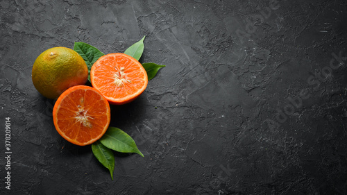 Mandarin on a black stone background. Citrus fruits. Top view. Free space for your text. © Yaruniv-Studio