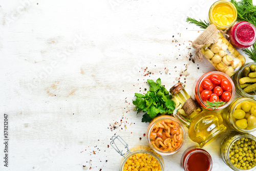 Background of food stocks in glass jars. Pickled vegetables and mushrooms. Top view.