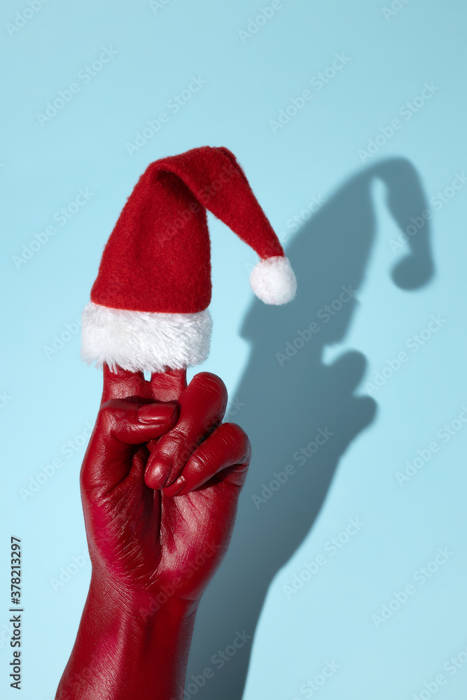 Hand painted in red holding Santa Claus cap on blue background. Minimal art Christmas concept. Hand painted in red holding Santa Claus cap on blue background. Minimal art Christmas concept.