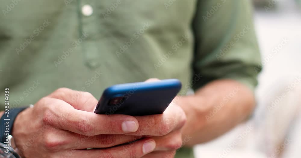 Close up shot of Caucasian man hands using mobile phone while standing on street. Male fingers typing and tapping on smartphone. Hands texting and scrolling outdoors. Technology concept Close up shot of Caucasian man hands using mobile phone while standing on street. Male fingers typing and tapping on smartphone. Hands texting and scrolling outdoors. Technology concept