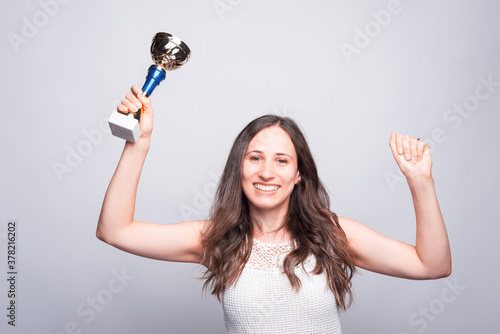 Cheerful young woman holding cup award, celebrating success