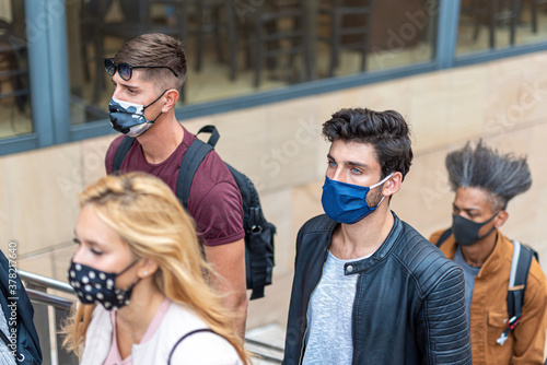 detail of the crowds in the city walking during the corona virus outbreak, multiracial people with faces covered with protective masks, new normal concept