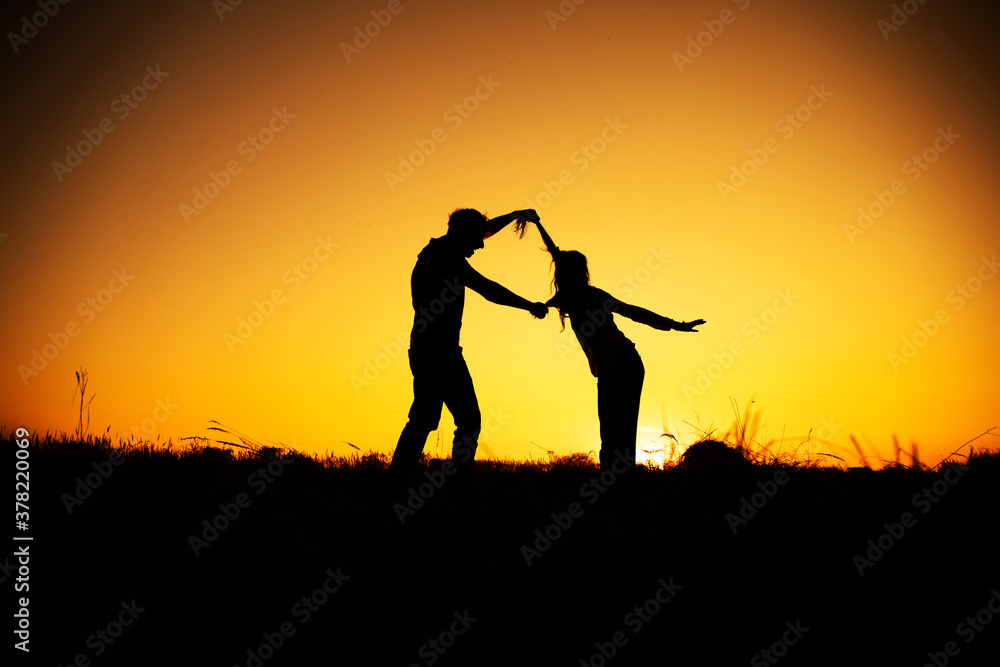 Young couple enjoying the sunset in the meadow. Couple in love. 
