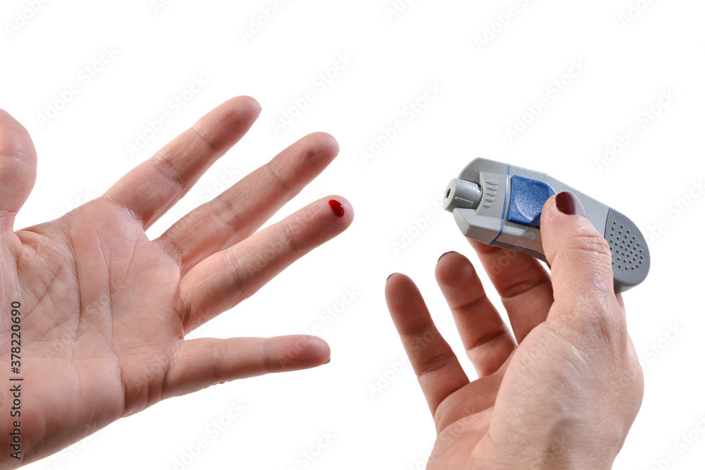 Close up of a woman hands using lancet on finger to check blood sugar level by glucose meter Close up of a woman hands using lancet on finger to check blood sugar level by glucose meter
