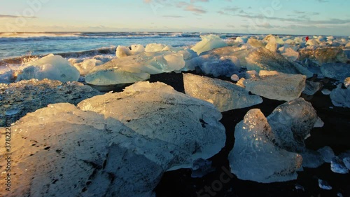 Slow motion Pan left, icebergs on Okulsarlon Beach at sunset photo