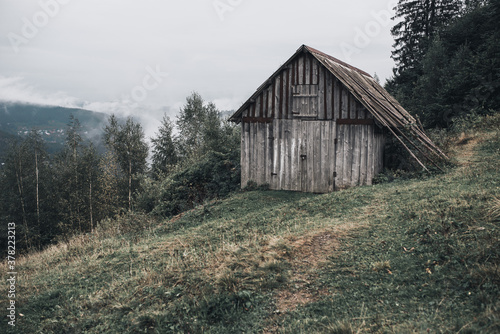 gray wooden house with boards in the Carpathian mountains. Yaremche. The most beautiful places in Ukraine. Tall spruce. fog over the forest. © Andrii