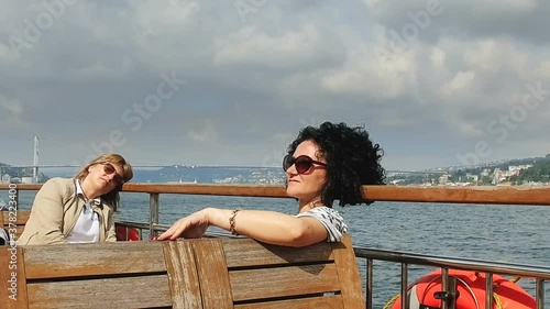 Smiling women are traveling by boat. At Bosphorus - relaxing on deck enjoying view from boat, Istanbul, Turkey photo