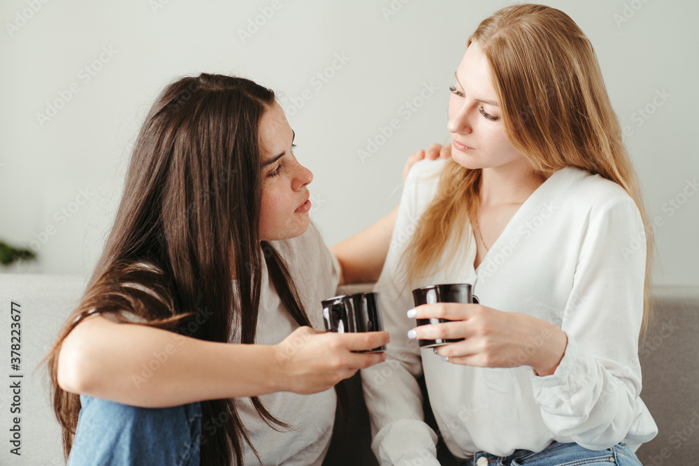 Young women drinking tea and talking indoors