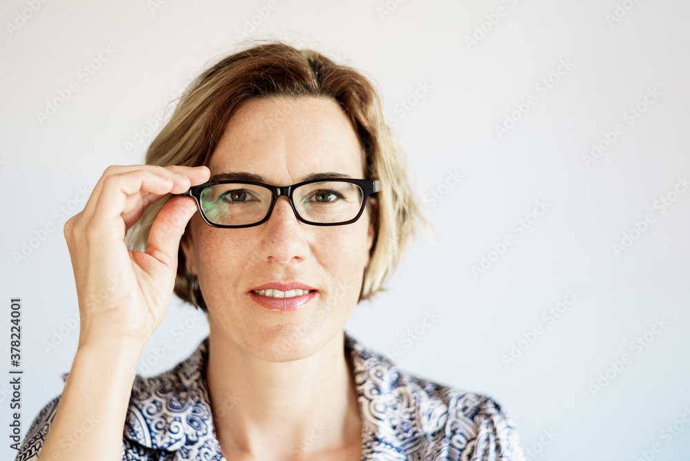 Real mature, active and modern woman, putting on her clear prescription glasses