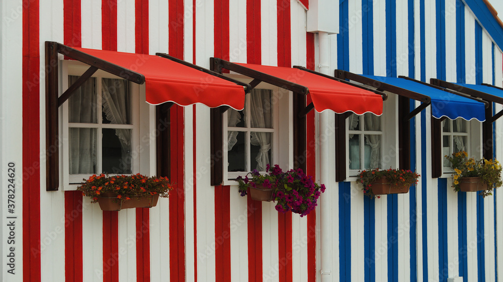 Janelas em paredes de casas pintadas ás riscas vermelhas e azuis - Portugal  foto de Stock | Adobe Stock