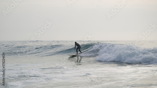 Surfista a surfar de pé em cima da prancha com fato de neoprene vestido photo