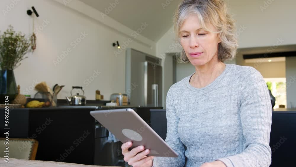 Mature woman at home buying products or services online using digital tablet and credit card - shot in slow motion Mature woman at home buying products or services online using digital tablet and credit card - shot in slow motion