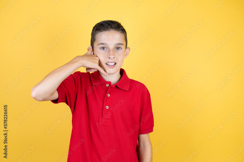 Young beautiful child boy over isolated yellow background smiling doing phone gesture with hand and fingers like talking on the telephone Young beautiful child boy over isolated yellow background smiling doing phone gesture with hand and fingers like talking on the telephone