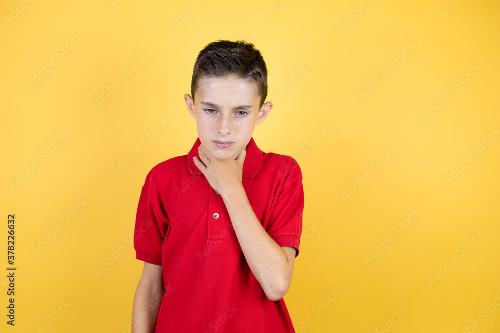 Young beautiful child boy over isolated yellow background touching painful neck, sore throat for flu, clod and infection Young beautiful child boy over isolated yellow background touching painful neck, sore throat for flu, clod and infection