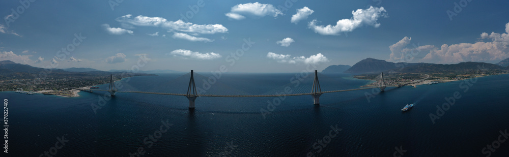 Obraz premium Aerial drone photo of world famous cable suspension bridge of Rio - Antirio Harilaos Trikoupis, crossing Corinthian Gulf, mainland Greece to Peloponnese, Patras